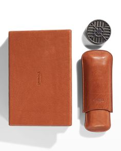 a brown leather case next to a wallet and an object on a white surface with a coin in it