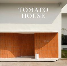 the entrance to tomato house is made out of wood and white tile with an orange door