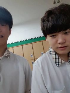 two young men standing next to each other in front of cupboards and counter tops