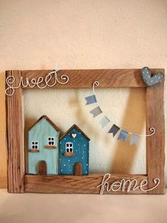 a wooden frame with two houses and a bunting banner on the side that says sweet home