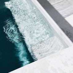 a person riding a skateboard on the edge of a swimming pool with water flowing down it