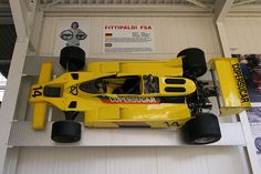 a yellow race car is on display in a building with white walls and ceilinging