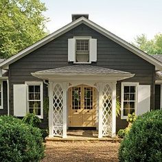 a small gray house with white shutters on the front door and windows in the side