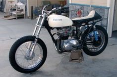 a white motorcycle parked in front of a garage