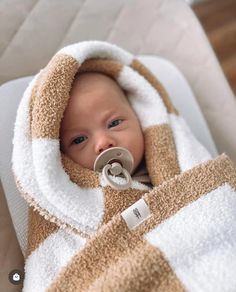 a baby wrapped in a brown and white blanket