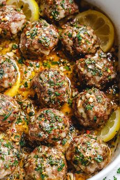 a white dish filled with meatballs and lemons