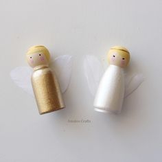 two small wooden angel figurines sitting next to each other on a white surface