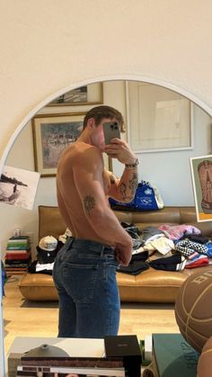 a shirtless man taking a selfie in front of a mirror