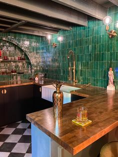 a kitchen with green tiles and wooden counter tops, two stools at the bar