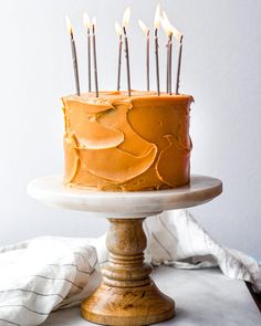 a cake with orange frosting and lit candles