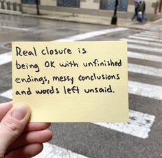 someone holding up a piece of paper that says real closure is being ok with unfinished endings, messy conditions and words left unsailed