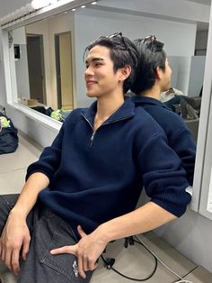 a young man sitting in front of a mirror