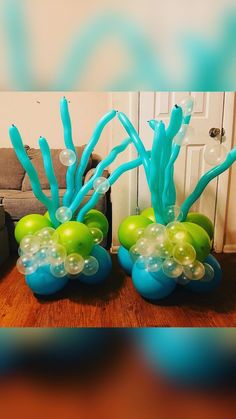 two blue and green vases with bubbles in them on a wooden table next to a couch