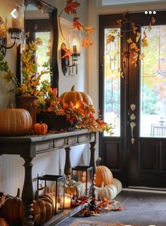 an entryway decorated for fall with pumpkins and gourds on the table