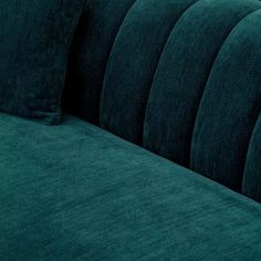 a close up view of a green velvet couch with two pillows on top of it