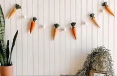 some carrots are hanging on a string next to a potted plant