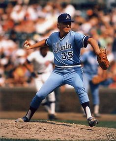 a baseball player pitching a ball on top of a field in front of a crowd