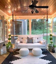 a porch swing bed with pillows and lights on the ceiling is decorated in black and white