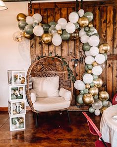 a room filled with lots of balloons hanging from the ceiling next to a wicker chair