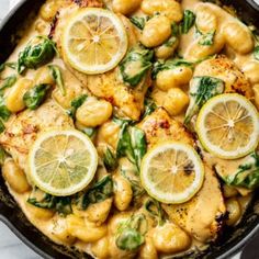 a skillet filled with chicken and lemons on top of a marble countertop