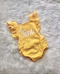 a yellow onesuit with the word mom written on it