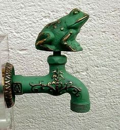 a green frog figurine sitting on top of a faucet