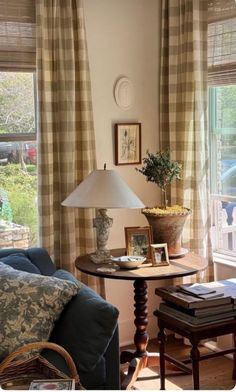 a living room filled with furniture and a lamp on top of a wooden table next to a window