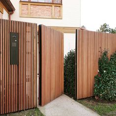 two wooden gates are open in front of a house