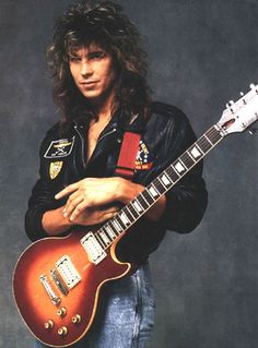 a man with long hair holding an electric guitar