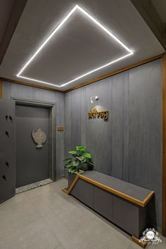 a room with a plant and some lights on the ceiling, along with a bench