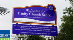 a sign for trinity church school is shown in front of trees and a wind vane