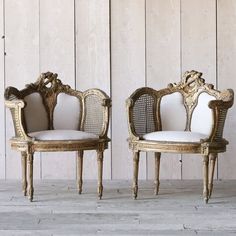 two chairs sitting side by side in front of a wooden wall