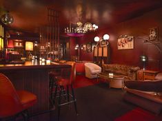 a dimly lit bar with chairs, stools and chandelier hanging from the ceiling