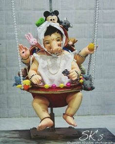 a figurine is sitting on a swing with beads around it's neck