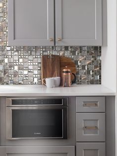 a kitchen with gray cabinets and stainless steel appliances