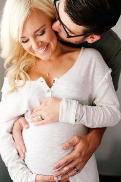 a man and woman hugging each other while holding their pregnant baby bump in front of the camera