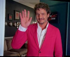 a man in a pink suit waves to the camera