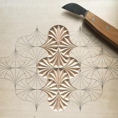 a wooden cutting board with an intricate design on it and a knife next to it