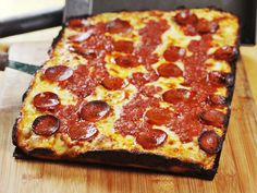 a pepperoni pizza sitting on top of a wooden cutting board