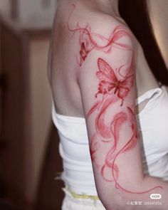 a woman with a red butterfly tattoo on her arm and shoulder is looking at the camera