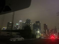 the city skyline is lit up at night with cars driving down the street in front of it