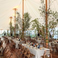 tables and chairs are set up in a tent with white linens for an event