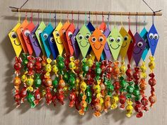 a group of colorful candy hanging from a wooden rack with eyes on them and smiling faces drawn on it