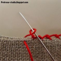 the needle is being used to sew together with red yarn on top of it