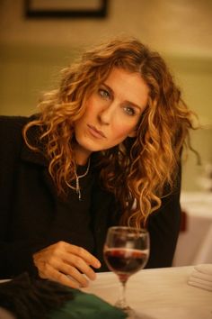 a woman sitting at a table with a glass of red wine in front of her