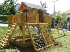 there is a wooden play set in the yard with climbing bars and ladders on it