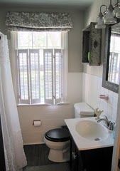 a white toilet sitting next to a sink in a bathroom under a window with shutters