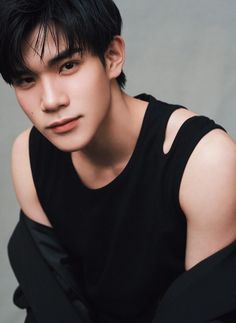 a young man with black hair is wearing a black shirt and posing for the camera