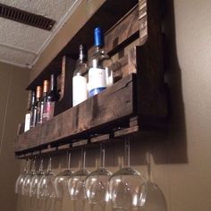 wine glasses and bottles are lined up on a wooden pallet mounted to the wall