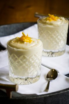 two desserts sitting on top of a table with spoons and napkins next to them